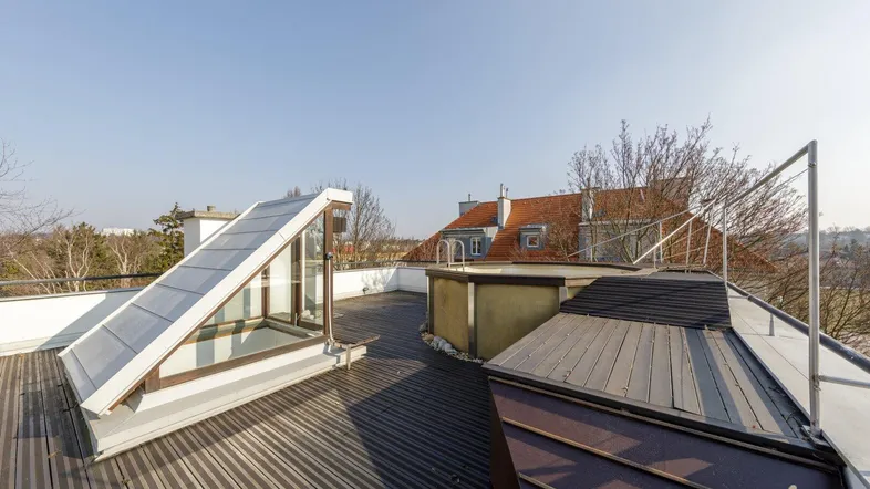 Große Dachterrasse mit Holzboden, Oberlicht und Blick auf die Umgebung unter blauem Himmel.