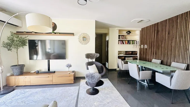 Geräumiger Wohn-Essbereich mit modernem Design, dunklem Fliesenboden und Holzakzenten.