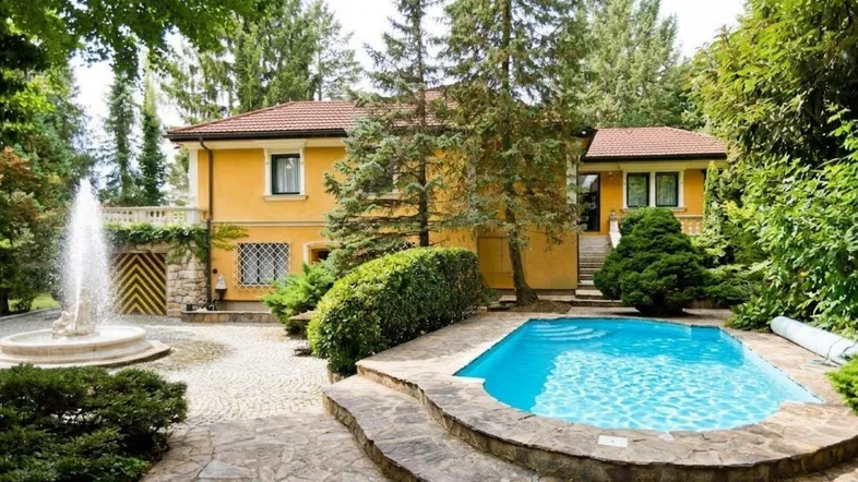 Großzügiger Gartenbereich mit Pool, Springbrunnen und gepflegter Bepflanzung vor der gelben Villa.