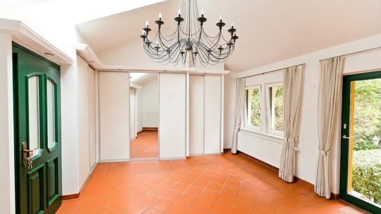 Helles Zimmer mit Terrakottaboden, Dachfenster und großem Spiegelschrank.