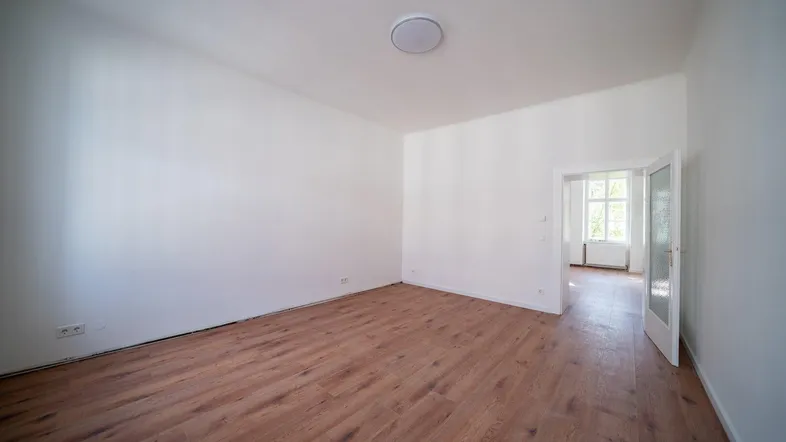 Helles, leeres Zimmer mit Holzboden und weiß gestrichenen Wänden, bereit zur individuellen Gestaltung.