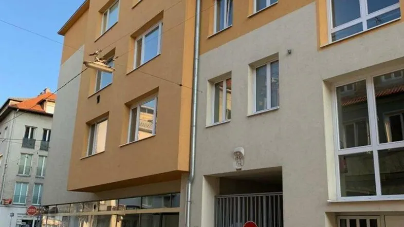 Mehrstöckiges Gebäude mit gelber und beiger Fassade und einem Garagentor auf Straßenniveau.