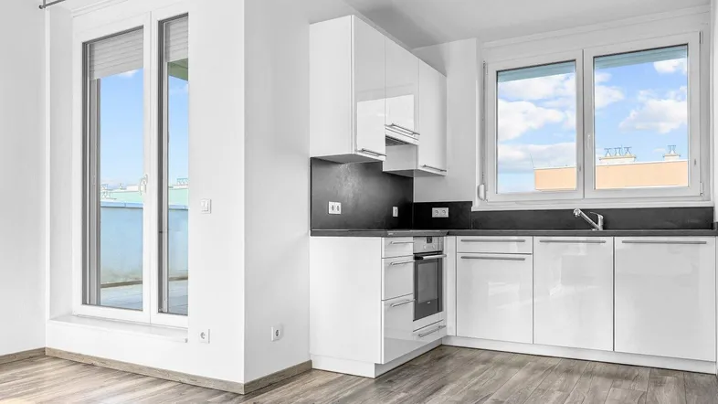 Moderne, offene Küche mit weißen Hochglanzfronten und Blick nach draußen.