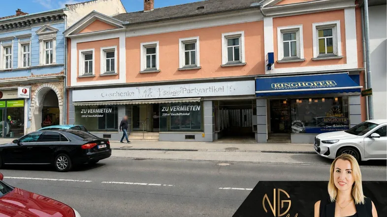 Historisches Gebäude mit Geschäften im Erdgeschoss und Wohnungen darüber, an einer belebten Straße gelegen.