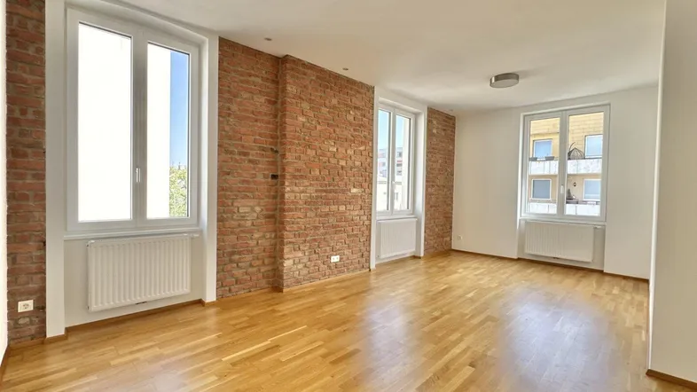 Helles, geräumiges Zimmer mit freigelegten Ziegelwänden und Parkettboden.