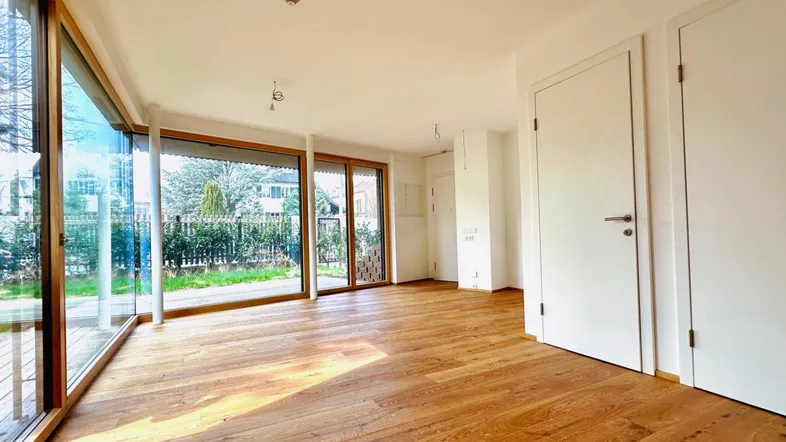 Heller Wohnraum mit Eichenparkettboden und großen Fensterfronten, die einen Blick in den Garten bieten.