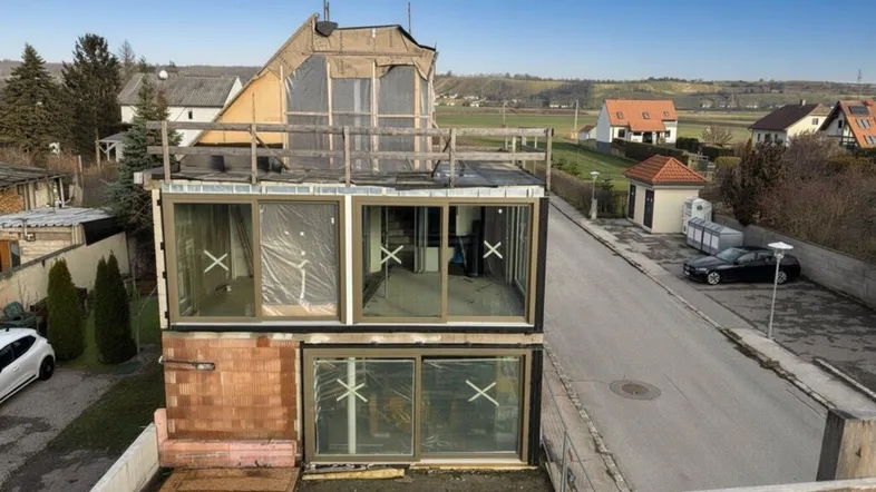 Neubau im Rohbauzustand mit großen Fensterfronten und weitem Blick auf die ländliche Umgebung.