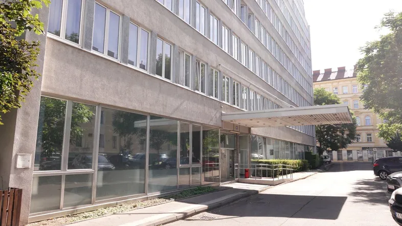Modernes Bürogebäude mit großen Fensterfronten und überdachtem Eingangsbereich an einem sonnigen Tag.