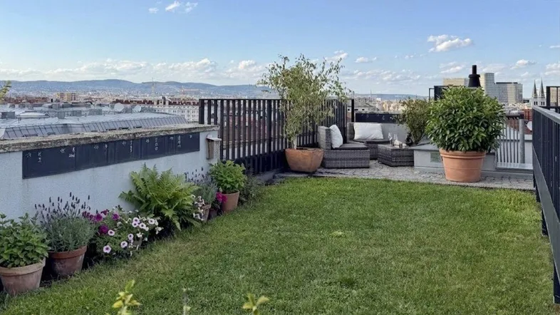 Weitläufige Dachterrasse mit Rasenfläche, Pflanzen und Panoramablick über die Stadt.