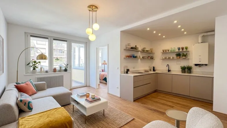 Heller offener Wohn- und Essbereich mit moderner Küche, Holzboden und Zugang zum Balkon.