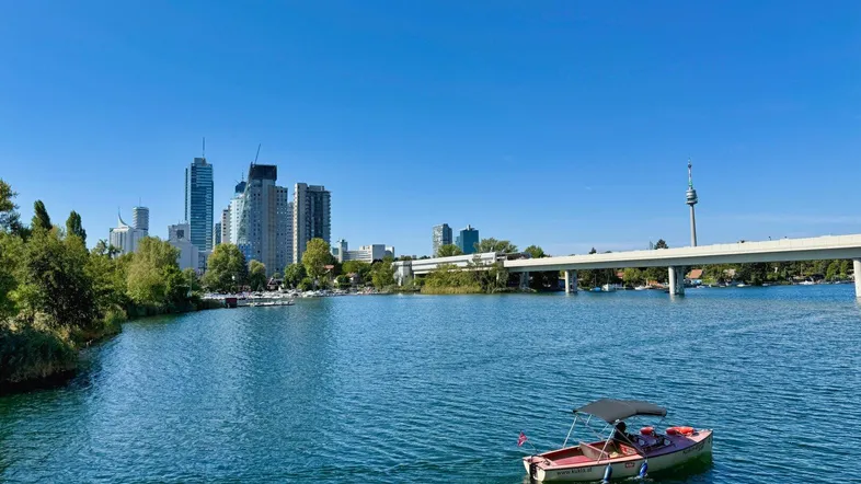 Panoramablick auf die moderne Stadtlandschaft mit Hochhäusern, Fluss und Brücke unter blauem Himmel.