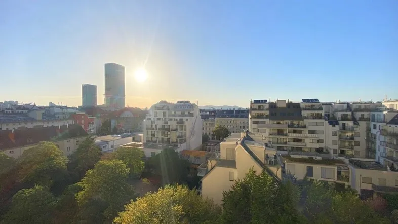 Panoramablick über die Stadt bei Sonnenuntergang mit modernen Gebäuden und viel Grün.