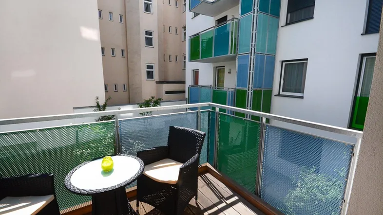 Balkon mit Sitzgelegenheiten und Blick auf die umliegenden Gebäude.