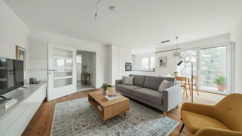 Heller, offener Wohn- und Essbereich mit moderner Einbauküche, Holzboden und Zugang zur Terrasse.