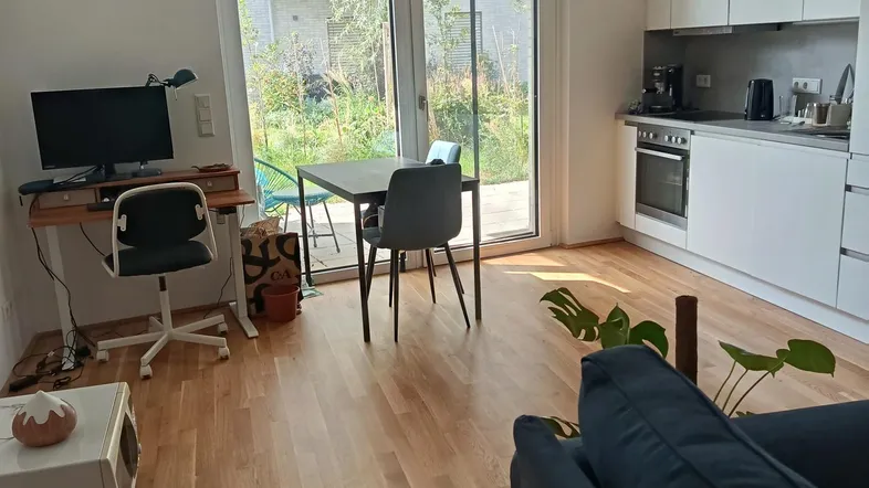 Helles Wohn-Esszimmer mit integrierter Küche, Parkettboden und direktem Zugang zum Garten.