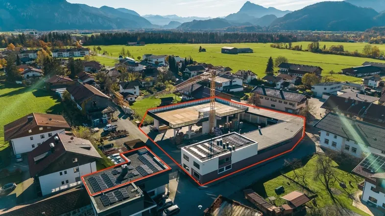 Luftaufnahme des Gewerbeobjekts mit umliegender Landschaft, Bergpanorama und Photovoltaikanlagen auf den Dächern.