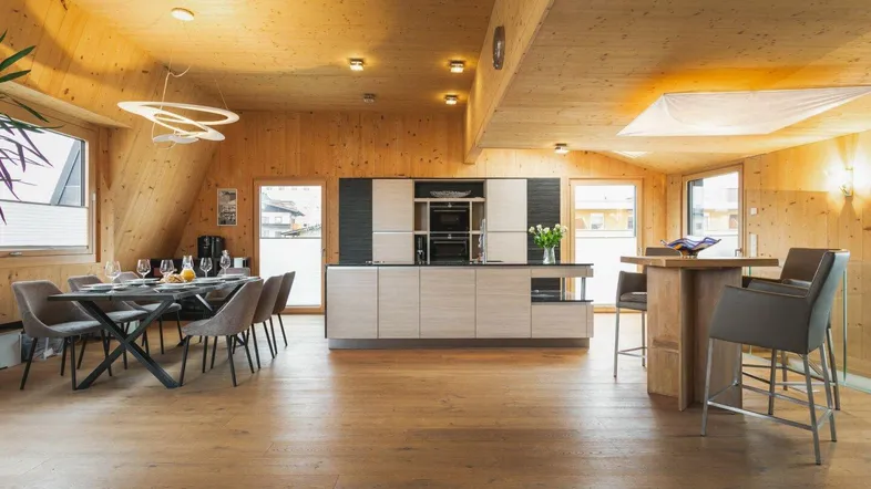 Geräumiger offener Wohn- und Essbereich mit moderner Küche, Holzböden und Dachschrägen.