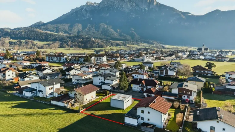 Luftaufnahme eines Baugrundstücks in einer ländlichen Wohngegend mit malerischem Bergblick.