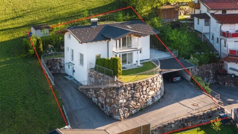 Luftaufnahme des Einfamilienhauses mit Grundstücksgrenzen und umliegender grüner Landschaft.