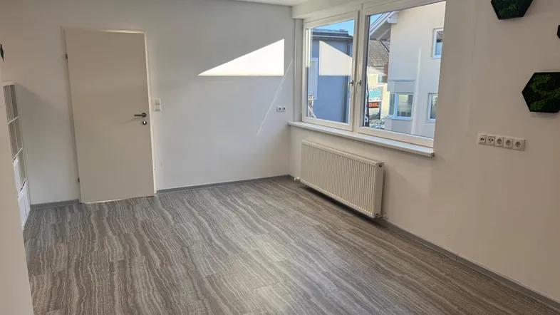 Heller Büroraum mit modernem Vinylboden, großen Fenstern und viel Tageslicht.