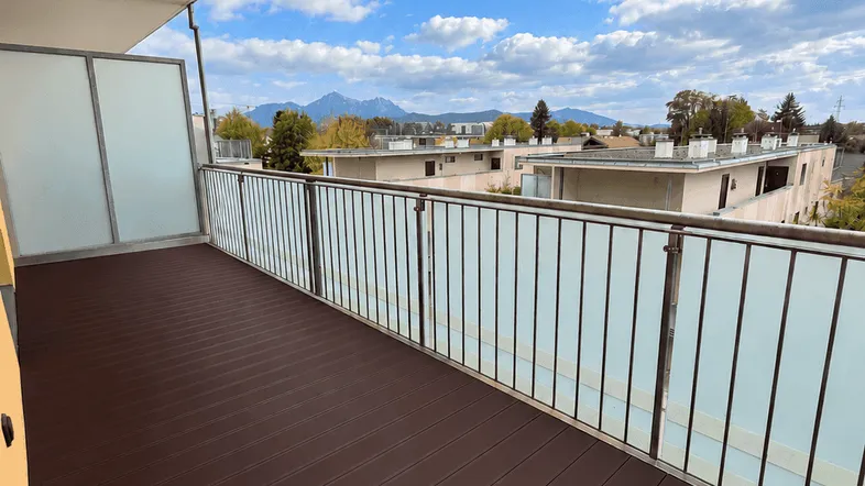 Geräumiger Balkon mit dunklem Holzboden und weitem Blick auf die umliegende Berglandschaft.