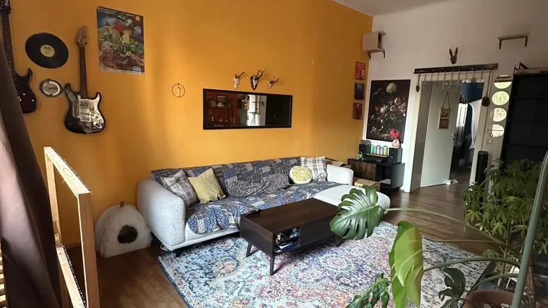 Geräumiges Wohnzimmer mit farbigen Wänden, Holzboden und gemütlicher Sitzecke.