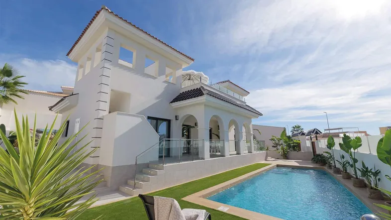 Elegante Villa mit großem Pool, gepflegtem Garten und sonniger Terrasse unter blauem Himmel.