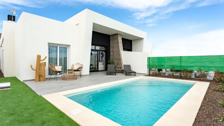 Moderne Villa mit privatem Pool, Sonnenterrasse und Liegestühlen unter blauem Himmel.