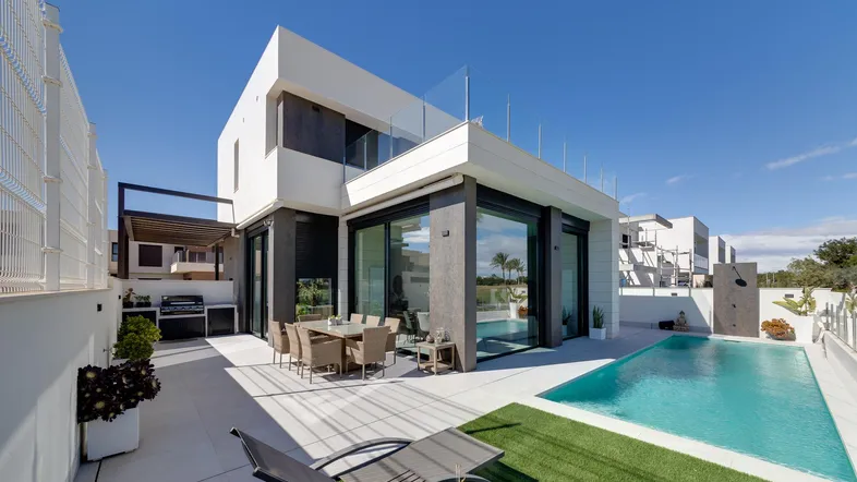 Moderne Villa mit privatem Pool, großer Terrasse und Essbereich im Freien unter blauem Himmel.