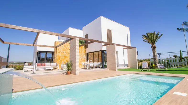 Moderne weiße Villa mit großem Pool, Holzterrasse, Kunstrasen und gemütlichen Sitzbereichen im Freien.