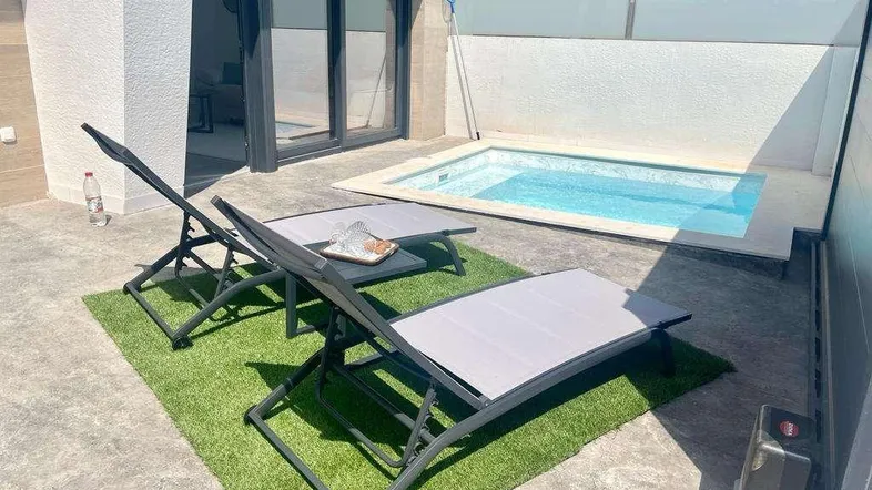 Sonnige Terrasse mit kleinem Pool, Liegestühlen und Zugang zum Innenbereich.