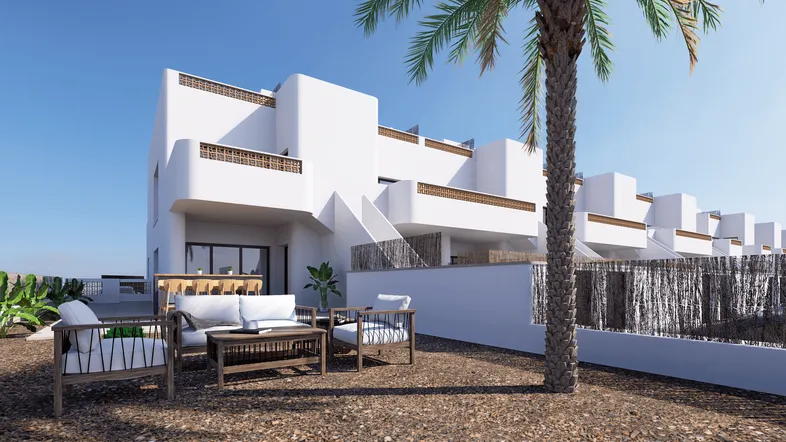 Moderne Reihenhäuser mit weißer Fassade, umgeben von mediterraner Vegetation und einer gemütlichen Terrasse.