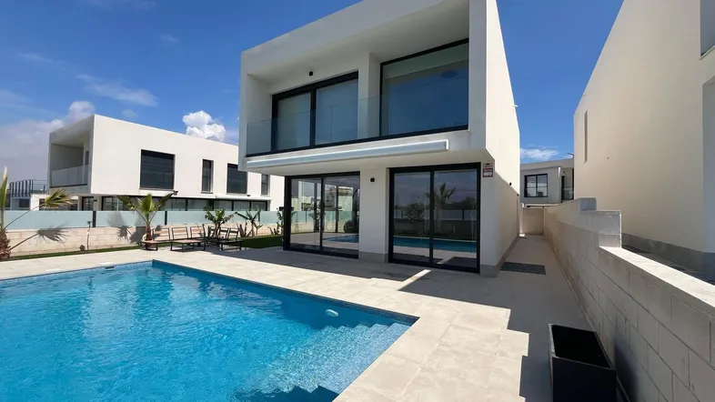 Moderne Villa mit privatem Pool und großzügiger Terrasse unter blauem Himmel.