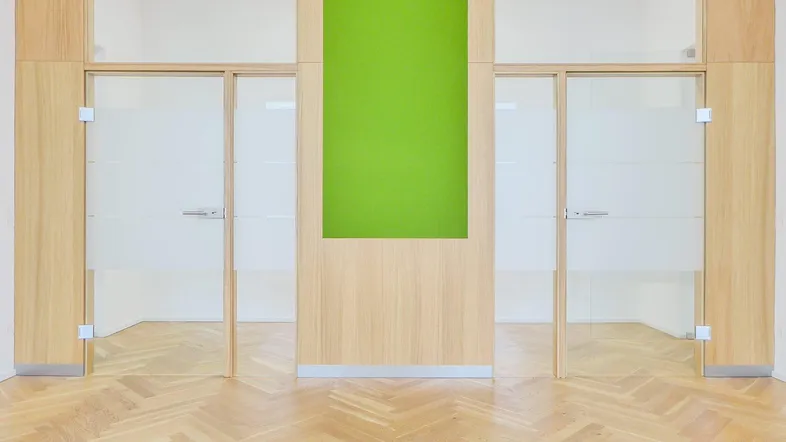 Moderner Bürobereich mit Holzvertäfelungen, satinierten Glastüren und Fischgrätparkettboden.