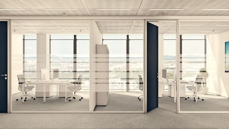 Modernes Büro mit Glaswänden, Teppichboden und Blick auf die Stadtlandschaft durch große Fenster.
