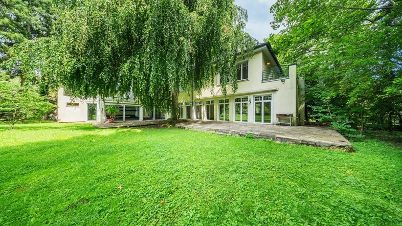 Rückansicht des Hauses mit mehreren Terrassentüren und einem großen, gepflegten Rasen.