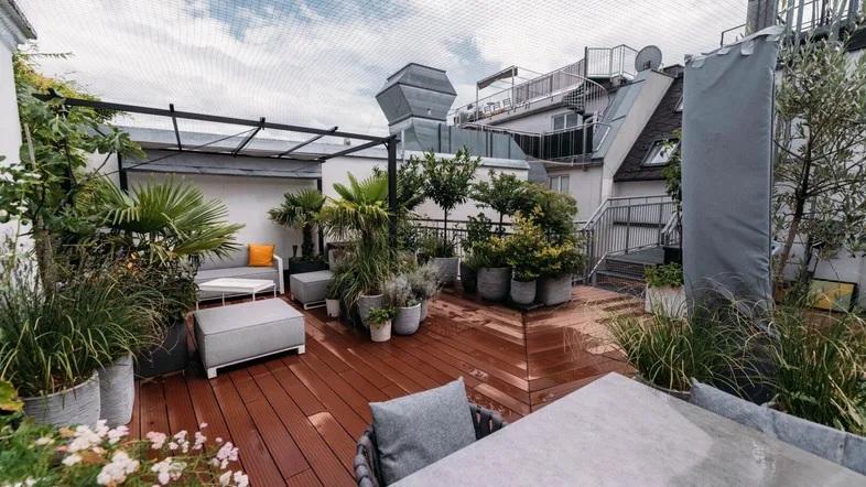 Geräumige Dachterrasse mit Holzdeck, bequemen Loungemöbeln und üppiger Bepflanzung für entspannte Stunden im Freien.