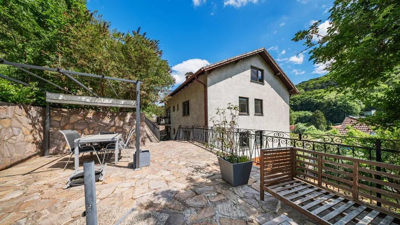 Große gepflasterte Terrasse mit Gartenmöbeln und Blick auf die grüne Umgebung.