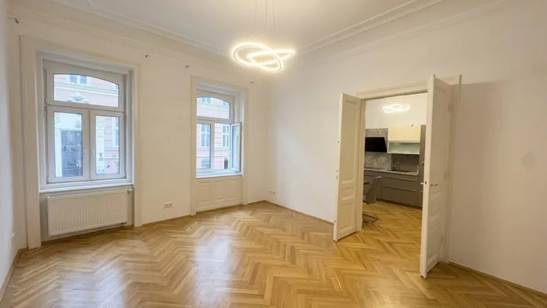 Helles Zimmer mit Fischgrätparkett, hohen Decken und Stuckverzierungen, bereit zur individuellen Gestaltung.