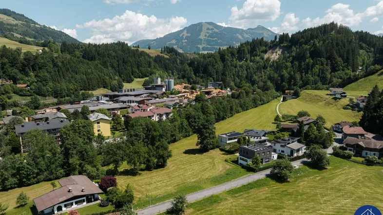 Weitläufige Luftaufnahme eines Dorfes in einem Tal mit majestätischen Bergen im Hintergrund.