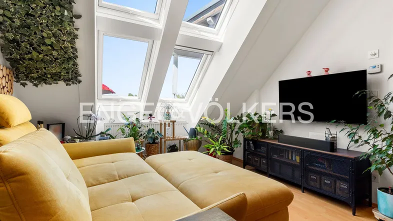 Helles Wohnzimmer im Dachgeschoss mit gemütlichem Sofa, vielen Pflanzen und großen Dachfenstern.