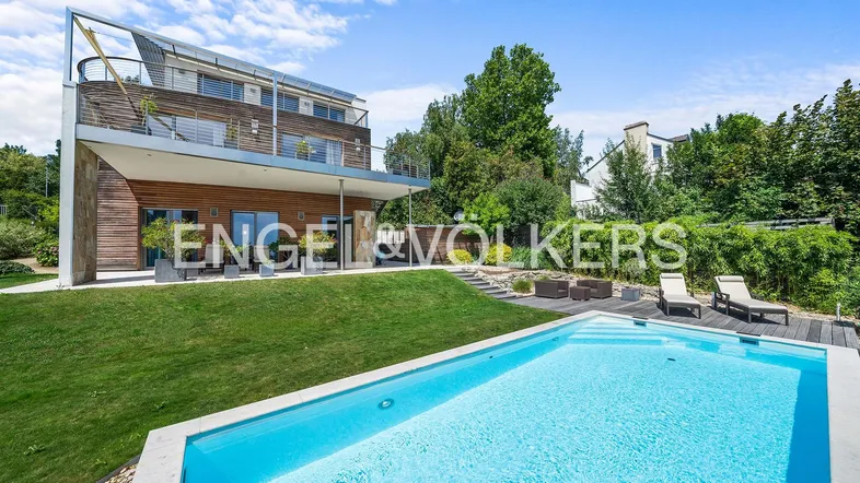 Moderne Villa mit großem Pool, gepflegtem Rasen und sonnigen Liegeflächen im Garten.
