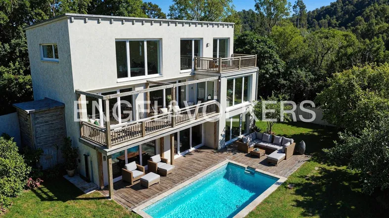 Moderne Villa mit mehreren Balkonen, großem Pool und weitläufigem Gartenbereich.