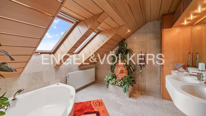 Helles Badezimmer im Dachgeschoss mit Badewanne, Doppelwaschbecken und Holzverkleidung.