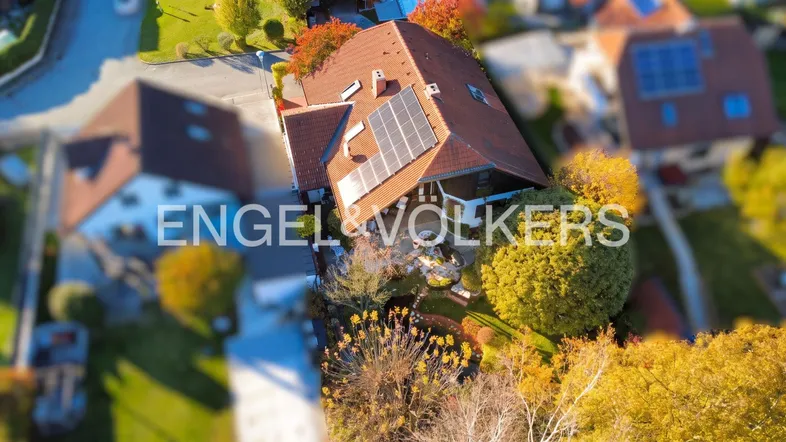 Luftaufnahme eines Einfamilienhauses mit Solaranlage auf dem Dach und gepflegtem Garten.