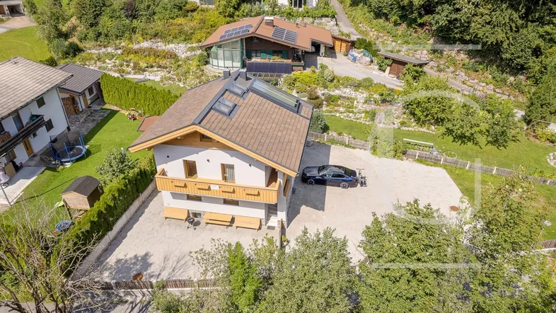 Luftaufnahme des modernen Hauses mit Satteldach, Balkonen und großem Vorplatz in grüner Umgebung.