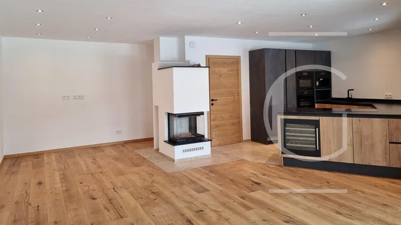 Geräumiger offener Wohn- und Essbereich mit modernem Kamin, Holzboden und integrierter Küche.