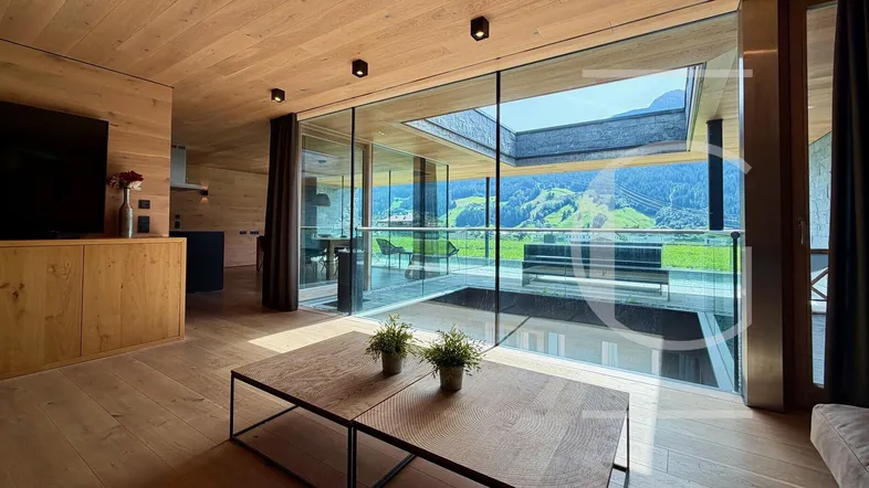 Helles Wohnzimmer mit Holzelementen, großen Glasfronten und beeindruckendem Bergblick.