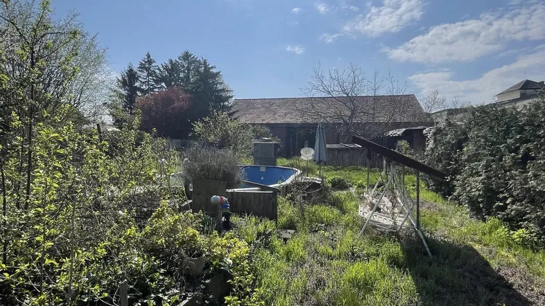 Sonniger, naturbelassener Garten mit einem kleinen Aufstellpool und viel Grünfläche.