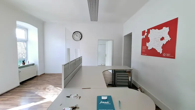 Geräumiges Büro mit L-förmigem Schreibtisch, Holzfußboden und einer Wandkarte, gut beleuchtet.